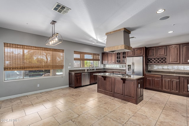 kitchen featuring dark brown cabinets, appliances with stainless steel finishes, a center island, sink, and decorative light fixtures