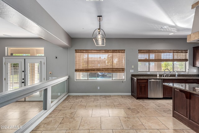 kitchen featuring sink, pendant lighting, stainless steel dishwasher, dark stone countertops, and light tile patterned floors