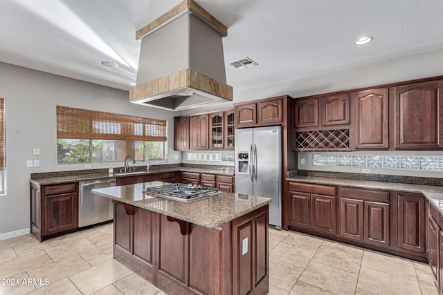 kitchen featuring light stone countertops, sink, a kitchen island, stainless steel appliances, and light tile patterned floors