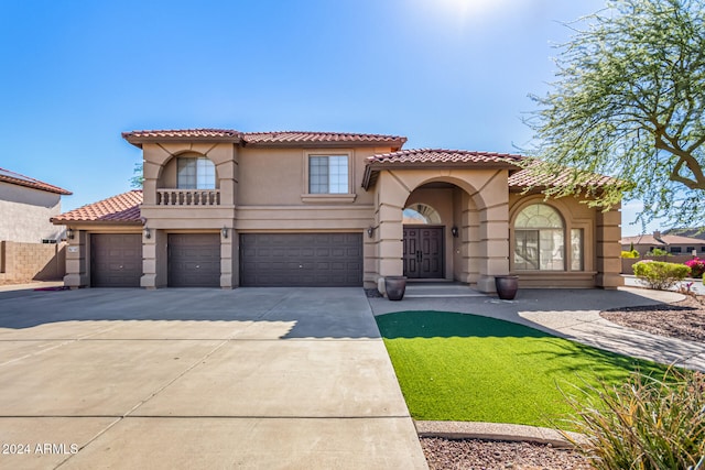 mediterranean / spanish-style house with a garage and a front lawn