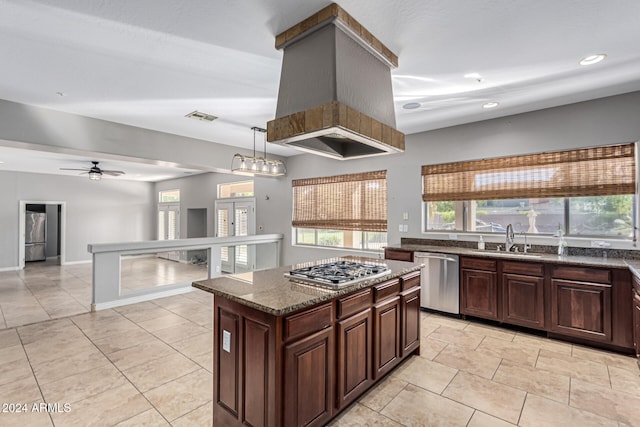 kitchen with ceiling fan, appliances with stainless steel finishes, a kitchen island, dark stone counters, and sink