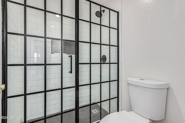 bathroom featuring a shower with door and toilet