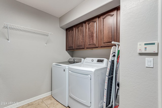 laundry area with cabinets, washer and dryer, and light tile patterned flooring