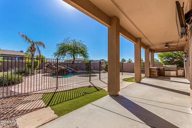 view of patio / terrace featuring ceiling fan, a fenced in pool, and an outdoor kitchen