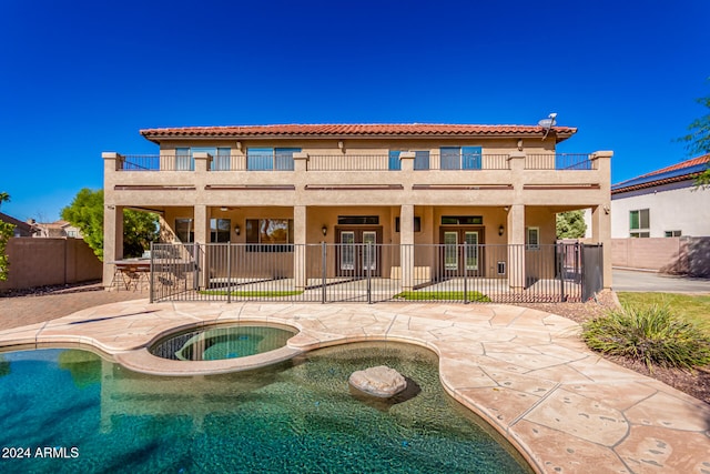 rear view of house featuring a balcony, a swimming pool with hot tub, and a patio