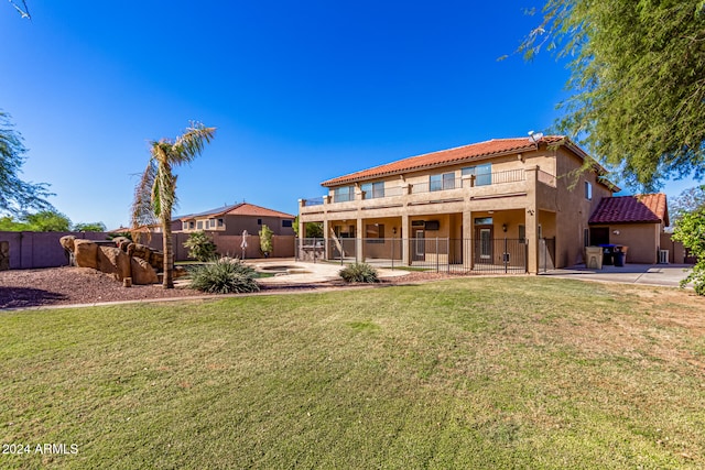 rear view of property featuring a balcony and a lawn