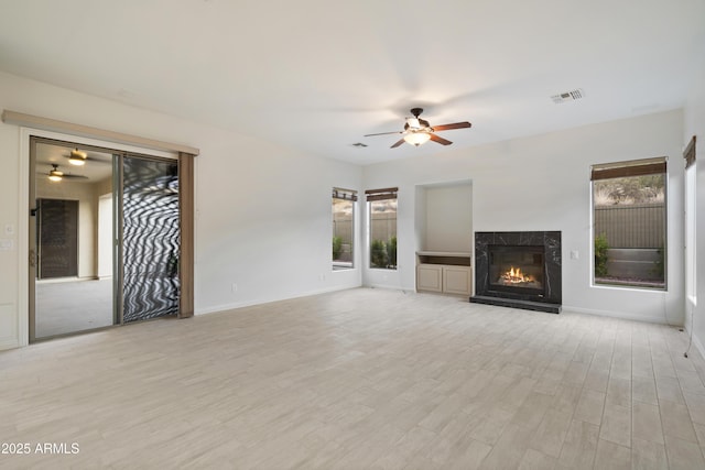 3551 W Hidden Mountain Ln, Anthem, AZ 85086 - unfurnished living room featuring light wood finished floors, a ceiling fan, baseboards, a high end fireplace, and visible vents