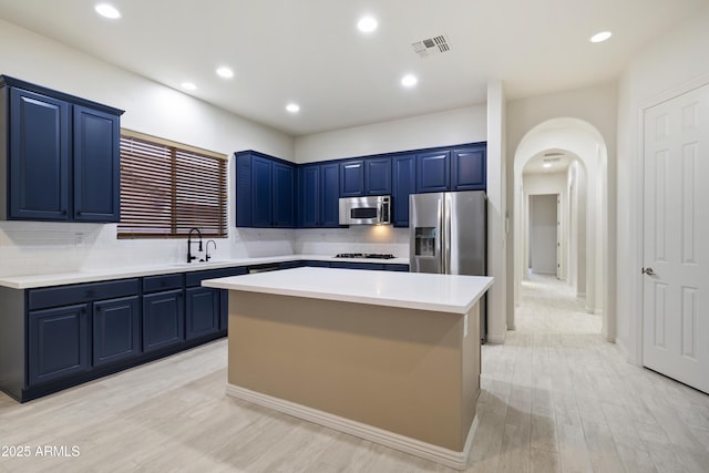 3551 W Hidden Mountain Ln, Anthem, AZ 85086 - kitchen with appliances with stainless steel finishes, arched walkways, blue cabinetry, and visible vents