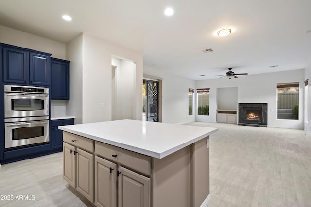 3551 W Hidden Mountain Ln, Anthem, AZ 85086 - kitchen with visible vents, double oven, a high end fireplace, light countertops, and a ceiling fan