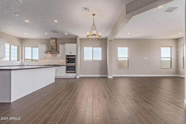 kitchen featuring white cabinetry, wall chimney exhaust hood, dark wood-type flooring, double oven, and pendant lighting