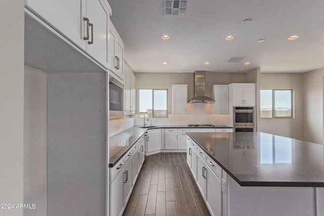 kitchen featuring white cabinets, plenty of natural light, dark hardwood / wood-style floors, and wall chimney range hood