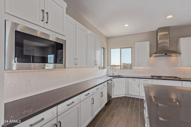 kitchen featuring white cabinets, wall chimney range hood, sink, tasteful backsplash, and stainless steel appliances