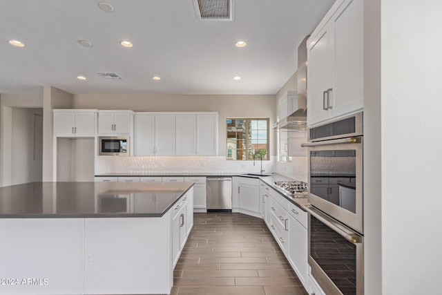 kitchen featuring appliances with stainless steel finishes, white cabinetry, a kitchen island, and sink