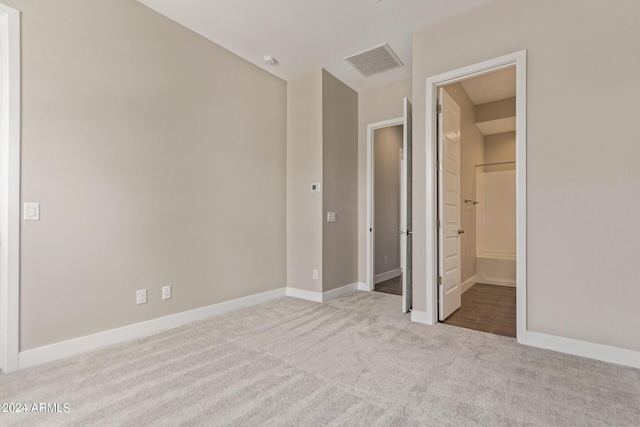 unfurnished bedroom featuring connected bathroom and light colored carpet