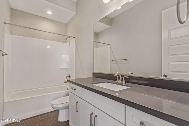 full bathroom with hardwood / wood-style flooring, vanity, toilet, and washtub / shower combination