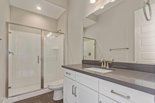 bathroom featuring vanity, toilet, wood-type flooring, and a shower with door