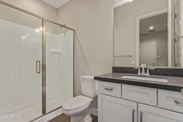 bathroom featuring vanity, toilet, and a shower with door