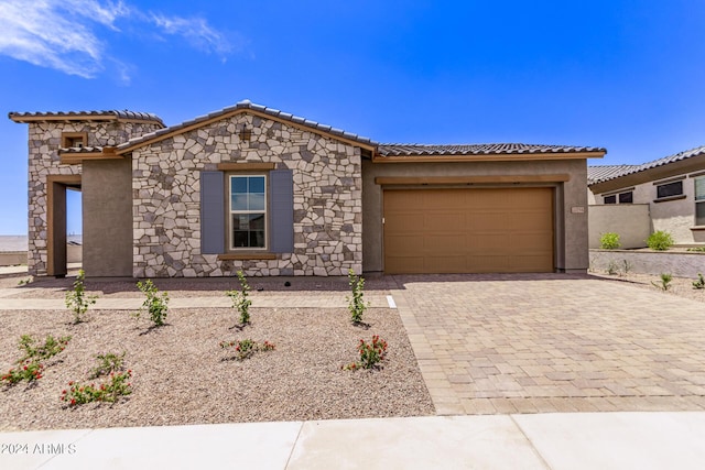 20755 W San Miguel Ave, Buckeye, AZ 85396 - view of front facade with stucco siding, a tile roof, decorative driveway, stone siding, and a garage