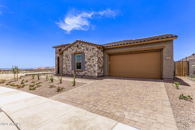 20755 W San Miguel Ave, Buckeye, AZ 85396 - view of front facade featuring fence, an attached garage, stone siding, a tiled roof, and decorative driveway