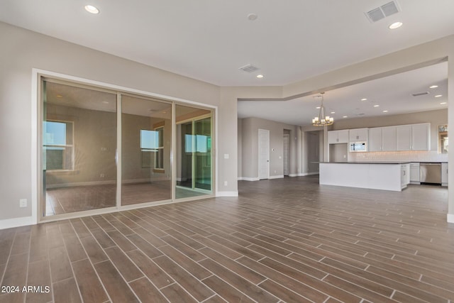 unfurnished living room featuring dark wood-type flooring and a notable chandelier