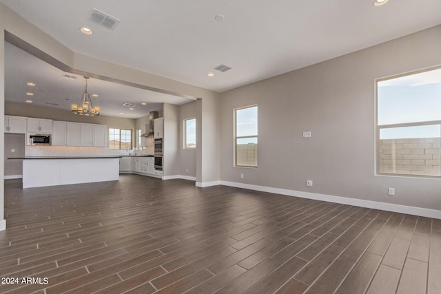 unfurnished living room featuring dark hardwood / wood-style flooring and an inviting chandelier