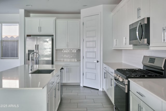 kitchen with stainless steel appliances, white cabinetry, sink, and tasteful backsplash