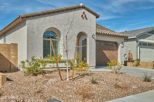 view of front of home featuring a garage, driveway, a tile roof, and stucco siding