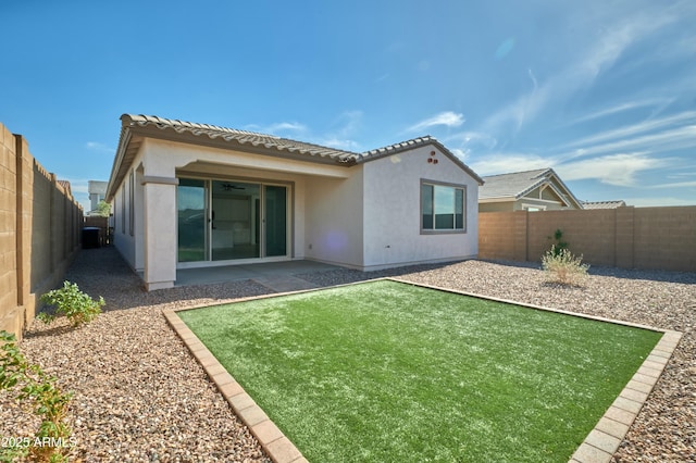 rear view of house with a fenced backyard, a tiled roof, and stucco siding