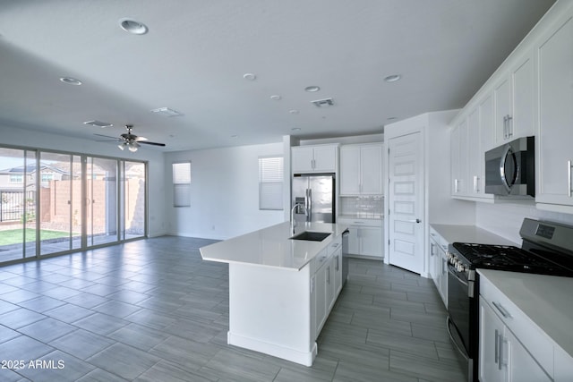 kitchen with sink, tasteful backsplash, a center island with sink, stainless steel appliances, and white cabinets