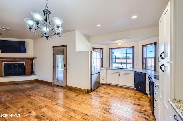 kitchen with light hardwood / wood-style flooring, a notable chandelier, black dishwasher, white cabinetry, and hanging light fixtures