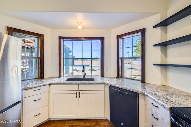 kitchen with white cabinetry, dishwasher, sink, light stone counters, and stainless steel fridge