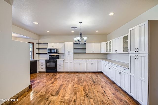 kitchen with black appliances, white cabinets, hanging light fixtures, light stone countertops, and light hardwood / wood-style floors