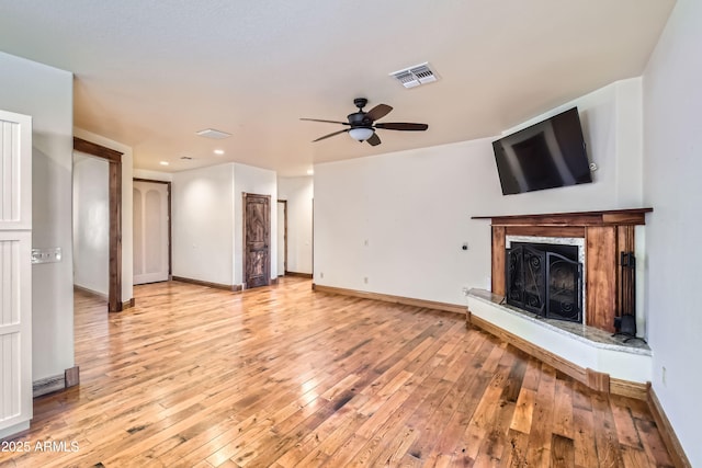 unfurnished living room featuring ceiling fan, light hardwood / wood-style floors, and a high end fireplace