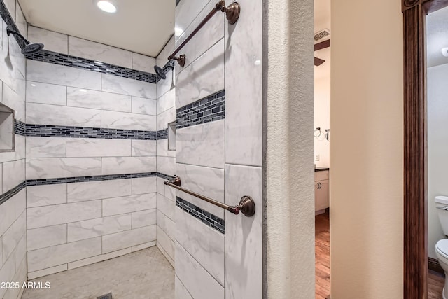 bathroom with a tile shower and toilet