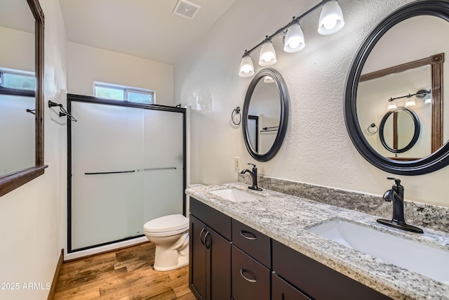 bathroom featuring hardwood / wood-style floors, vanity, toilet, and a shower with shower door