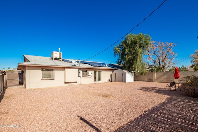 rear view of house featuring a shed, cooling unit, and solar panels