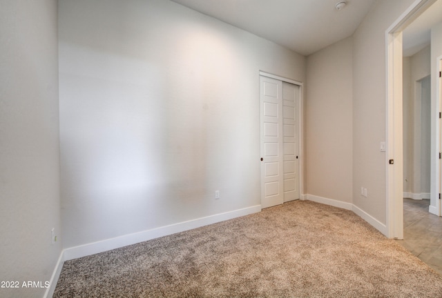 unfurnished bedroom with light carpet and a closet