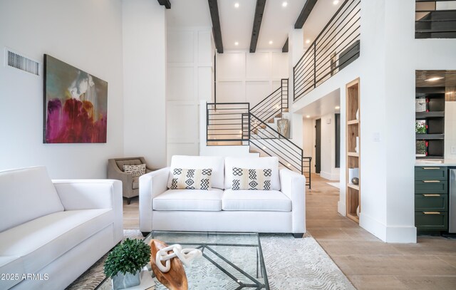 living area with recessed lighting, wood finished floors, a high ceiling, stairs, and beam ceiling