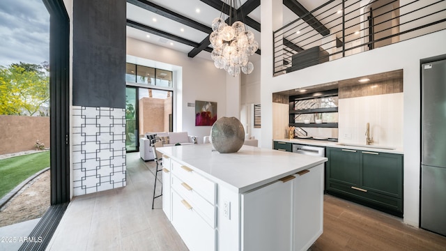 kitchen featuring a center island, light countertops, beamed ceiling, light wood finished floors, and a sink