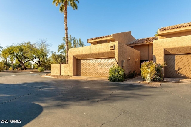 view of front facade featuring driveway, stucco siding, an attached garage, and a tile roof