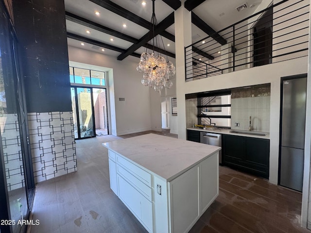 kitchen with visible vents, a center island, baseboards, a sink, and beam ceiling