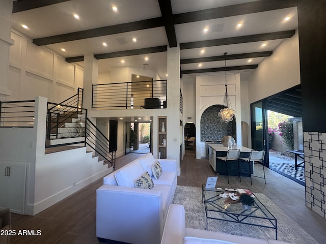 living area with arched walkways, a towering ceiling, beamed ceiling, and wood finished floors