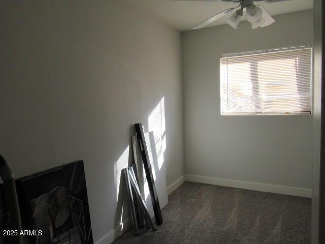 spare room with ceiling fan and dark carpet