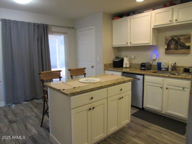 kitchen featuring dark hardwood / wood-style flooring, stainless steel dishwasher, white cabinets, and a center island