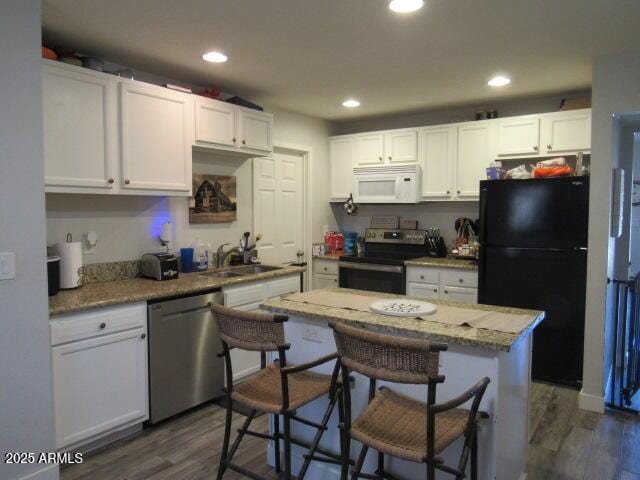 kitchen with appliances with stainless steel finishes, sink, white cabinetry, and dark hardwood / wood-style floors