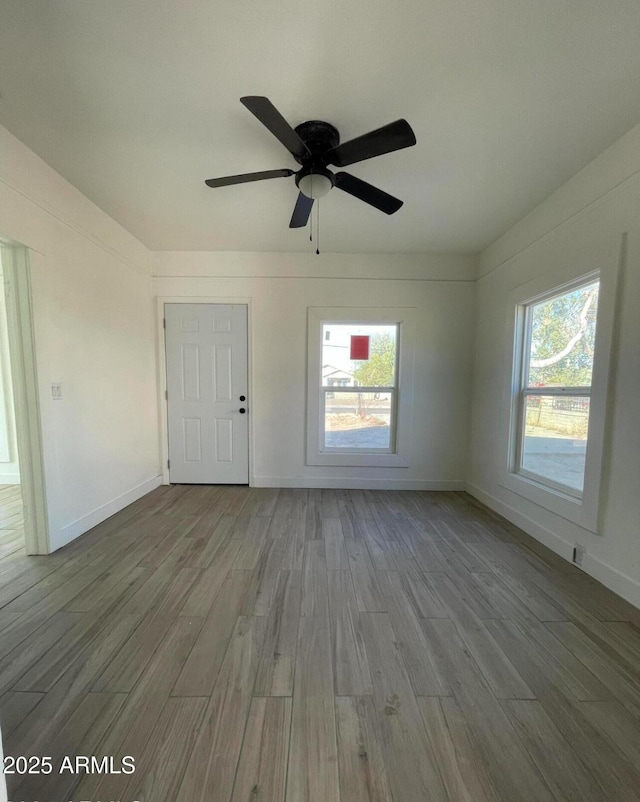 unfurnished living room featuring a ceiling fan, a wealth of natural light, and wood finished floors