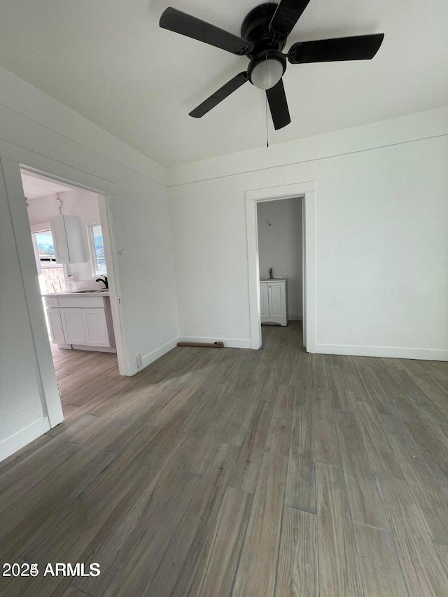 interior space with a sink, ceiling fan, wood finished floors, and baseboards