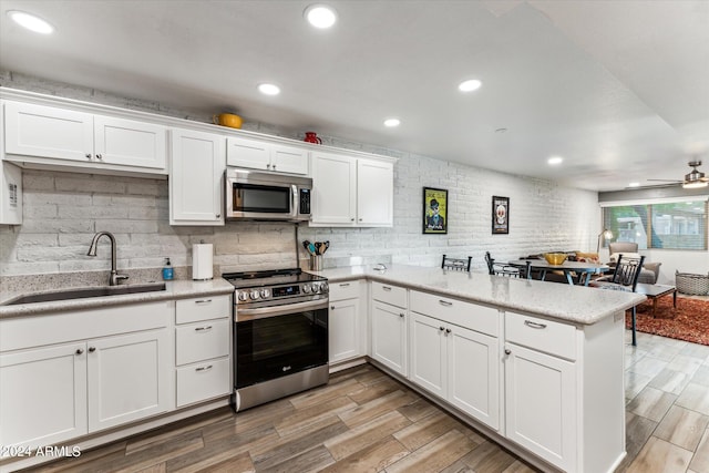 kitchen with appliances with stainless steel finishes, light hardwood / wood-style flooring, white cabinets, and sink