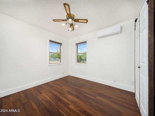 spare room featuring a wall unit AC, ceiling fan, and dark wood-type flooring