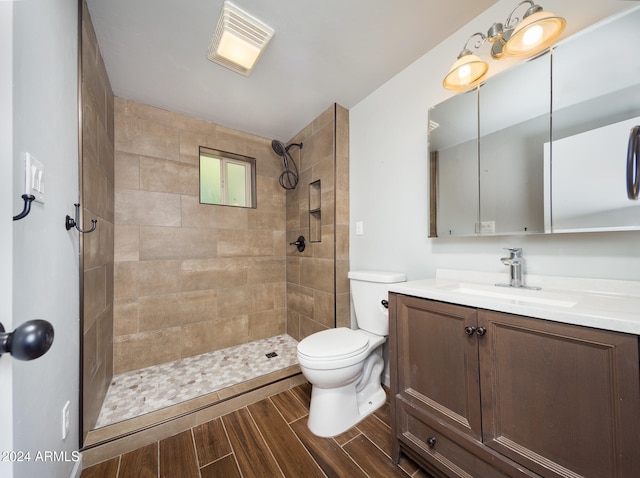 bathroom with a tile shower, vanity, and toilet